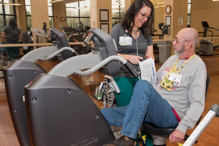 Man in grey sweatshirt on stationary bike next to nurse