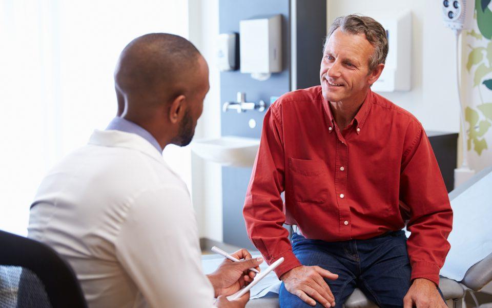 Male Patient And Doctor Have Consultation In Hospital Room