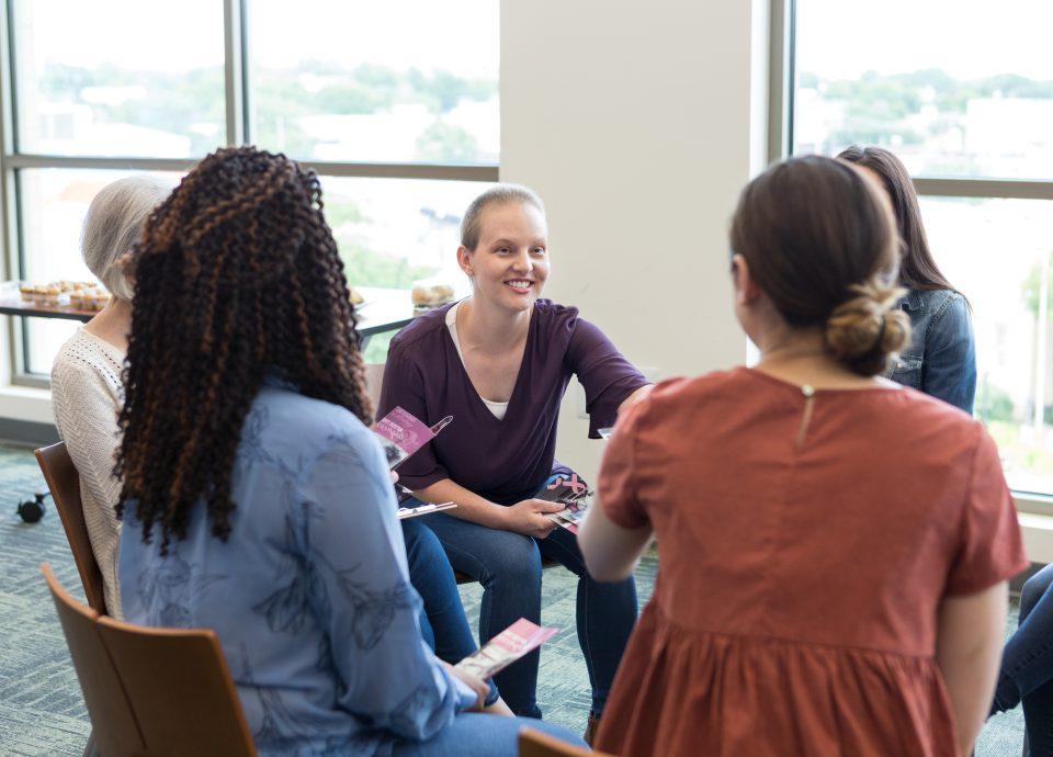 Women meet and shake hands at cancer recovery meeting